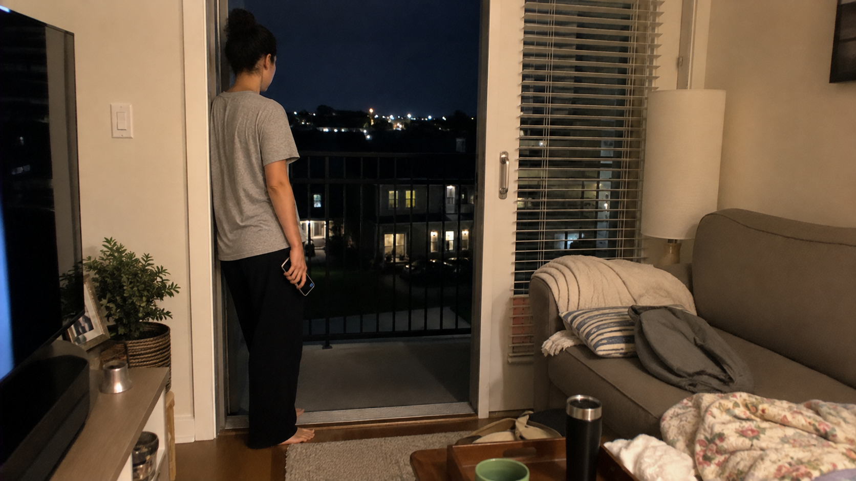 A woman reflecting on ending an affair while standing alone at home at night.