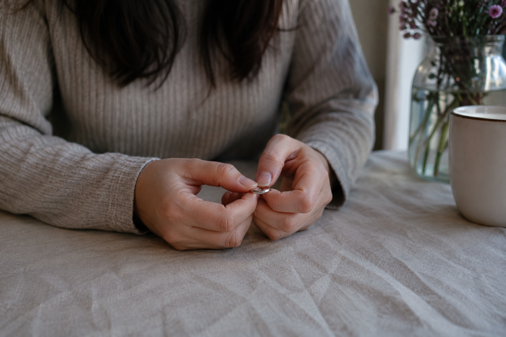 A woman holding a wedding ring, pondering the idea of getting back together with an ex husband.